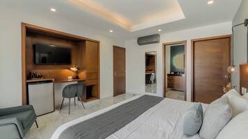 A modern hotel room with a bed, desk, chair, and a TV.
