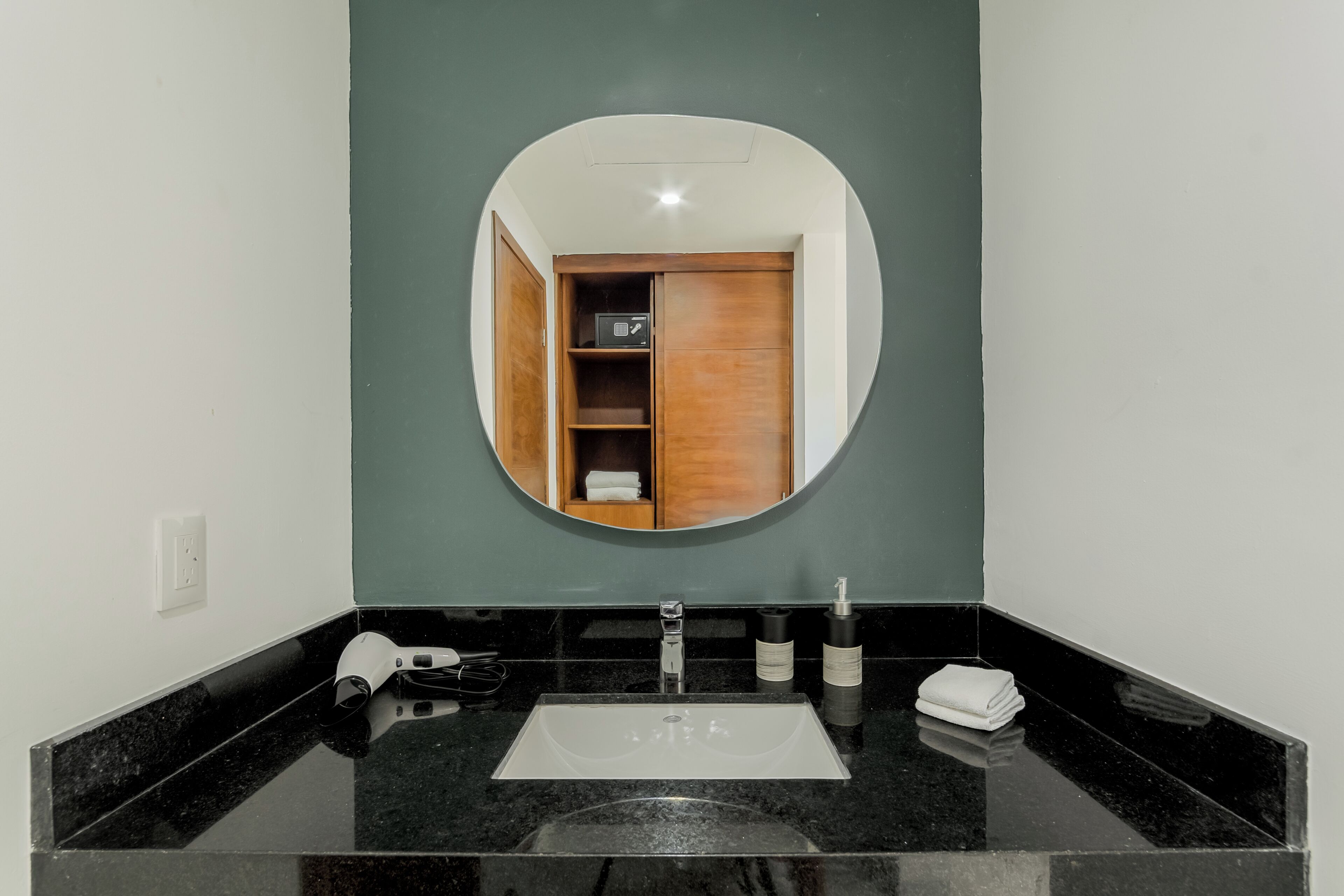 A bathroom with a black marble sink, a mirror, a towel, and a wooden cabinet.