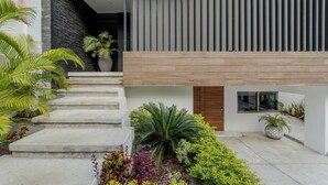A modern building with a staircase, a wooden door, and a potted plant.