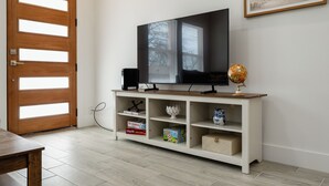A room with a wooden door, a TV on a white stand, and a globe. - Brand New Home Near Downtown (Sulphur Springs)