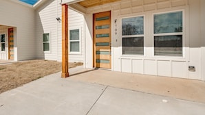 A residential building with a wooden door, a garage door, and a number '709' on the wall. - Brand New Home Near Downtown (Sulphur Springs)