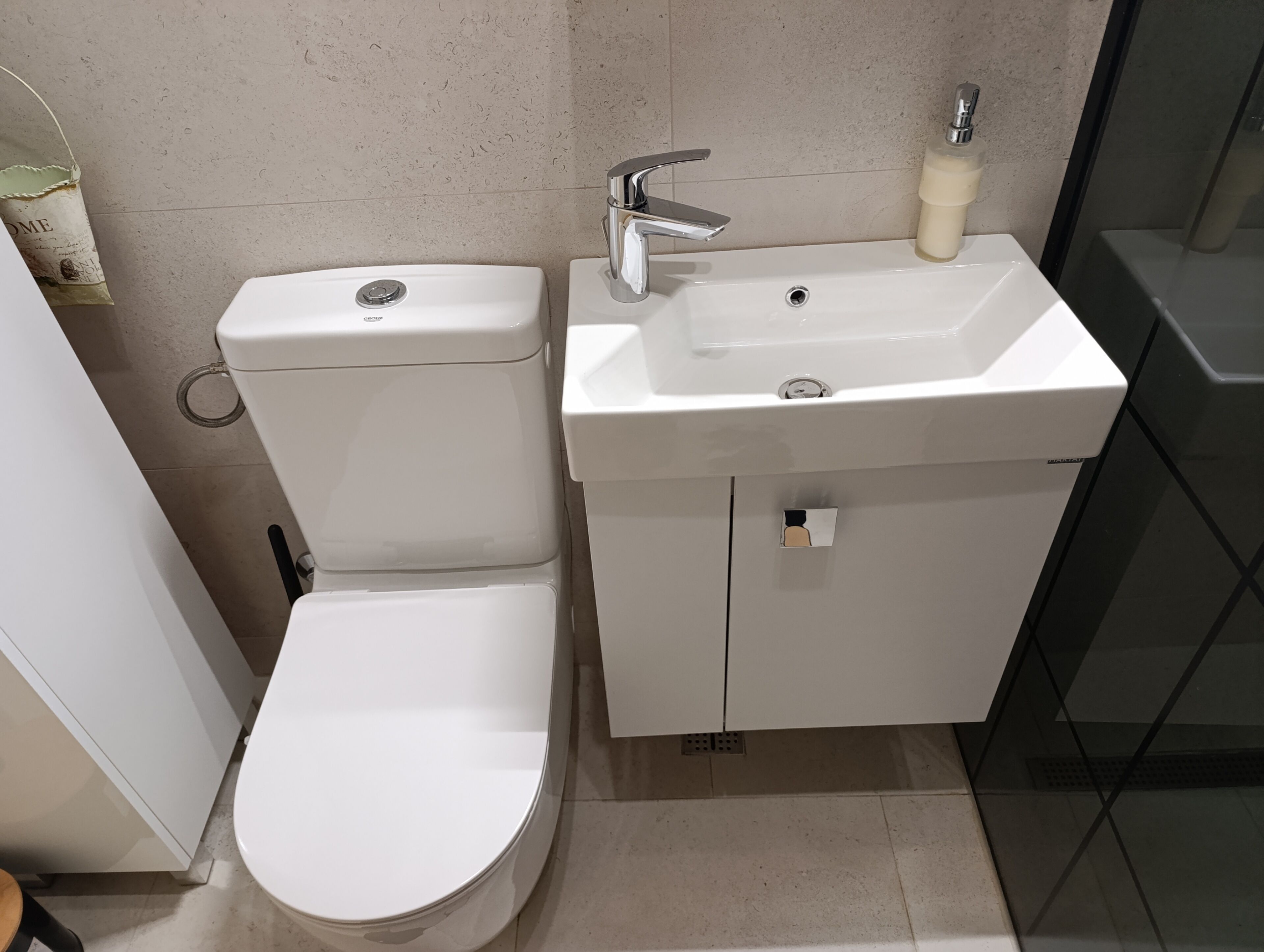 A bathroom with a toilet, sink, and cabinet.