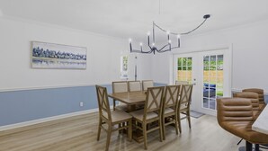 Comedor con mesa y sillas de madera, un candelabro y un cuadro en la pared.