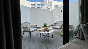 A balcony with a round table, two chairs, and a view of buildings.