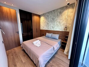 A modern bedroom with a large bed, wooden wardrobe, and a patterned wall.