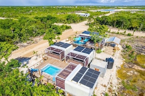 A resort with multiple solar panel installations, a swimming pool, and a beach area.