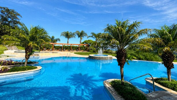 A large outdoor swimming pool with palm trees and a gazebo. - Luxury 2-Story Penthouse with Private Jacuzzi (Río Oro)