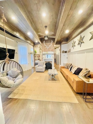 A spacious living area with a hanging chair, sofa, and a fireplace. - The Modern Victorian Charmer Hot Tub 5 bedroom 4 bath (Atlanta)