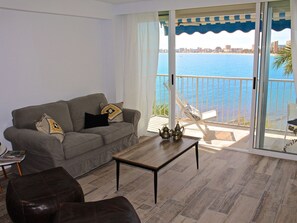 Ein Wohnzimmer mit einer Couch, einem Couchtisch und Meerblick vom Balkon.