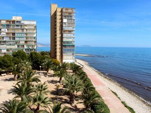 A beachfront property with a sandy beach, palm trees, and two multi-story buildings. - APARTAMENTO CABO AZUL by Interhome (El Campello/Villajoyosa)