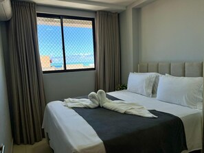 Ein Hotelzimmer mit Bett, Vorhängen, einem Fenster mit Aussicht und einem Kopfteil.