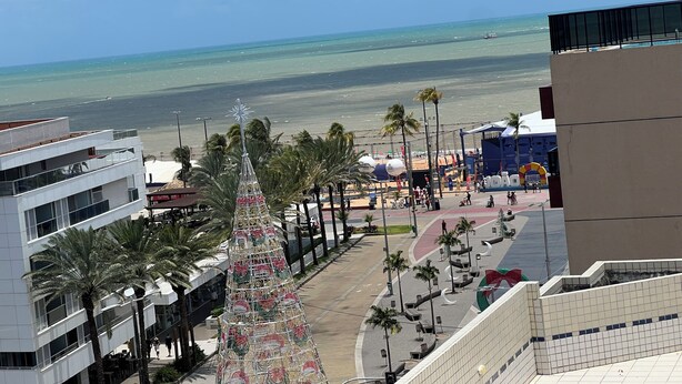 Un bâtiment moderne avec une façade en verre, un sapin de Noël décoratif et une vue sur la plage.
