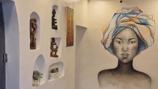 Un pasillo con iluminación empotrada, un mural grande en la pared y piso de baldosas.