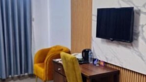 Una habitación con una mesa de comedor, dos sillas amarillas, un televisor montado en la pared y un diseño de panel de madera.