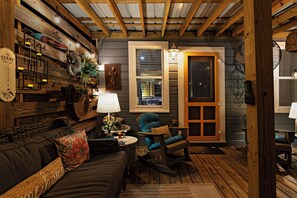 A cozy room with a wooden ceiling, a rocking chair, a sofa, and a lamp. - Lovely 2-bedroom waterfront cottage with many outdoor activities and charm (Foley)