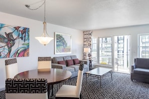 A modern living room with a sofa, a dining table, and a patterned rug. - Bright 2-bedroom apartment with AC in lovely Surfside (Surfside)