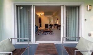 A room with a sliding glass door leading to a living area, a small table, and two chairs.