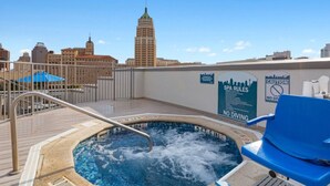 Una piscina en la azotea con vistas al horizonte urbano, un cartel que indica las normas del spa y un aviso sobre la prohibición de buceo.