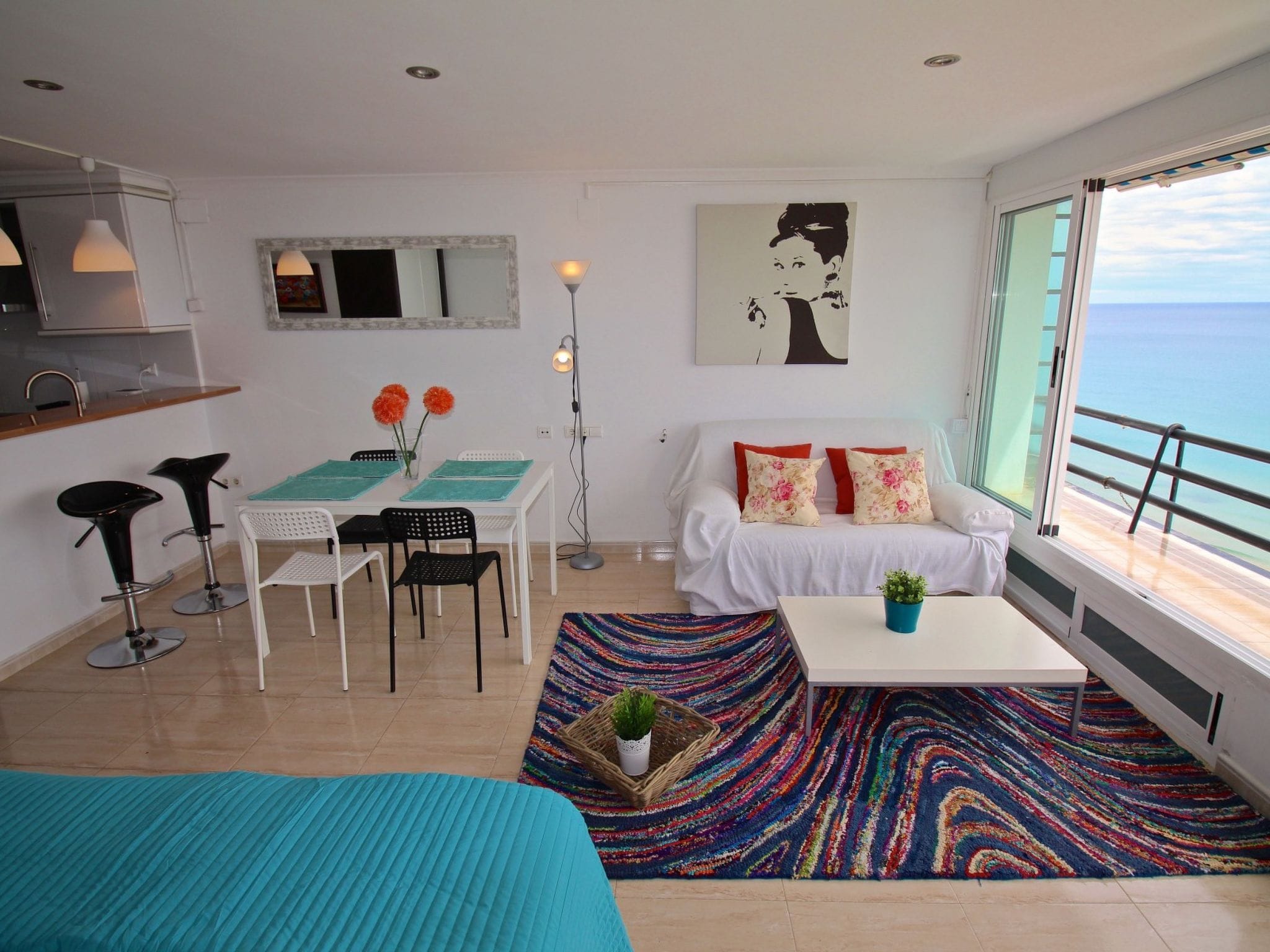 A modern living room with a sofa, coffee table, and a view of the sea.