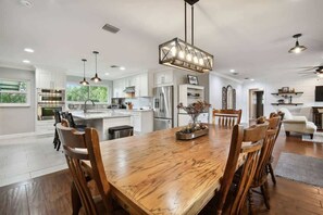 Een ruime keuken met moderne apparatuur, een eethoek met houten stoelen en een centraal gelegen kookeiland.