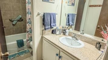 A bathroom with a sink, mirror, towel rack, shower curtain, and a decorative rug.