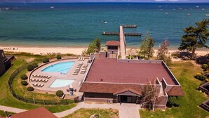 Um hotel com piscina, vista para a praia e um cais.