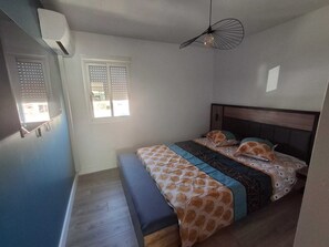 Ein Schlafzimmer mit einem Bett, einer Bank, einem Deckenventilator und einem Fenster mit Jalousien.