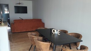 Een eetgedeelte met een zwarte tafel, zes stoelen en een hanglamp.