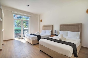 A hotel room with two beds, a balcony, and a view of the outside.