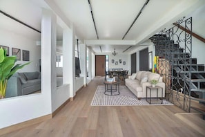 A spacious living area with a sofa, coffee table, and staircase.