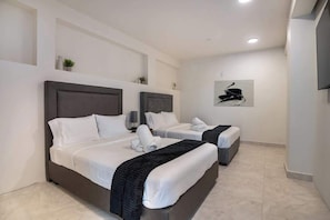 A hotel room with two beds, a flat-screen TV, and a wall-mounted artwork.