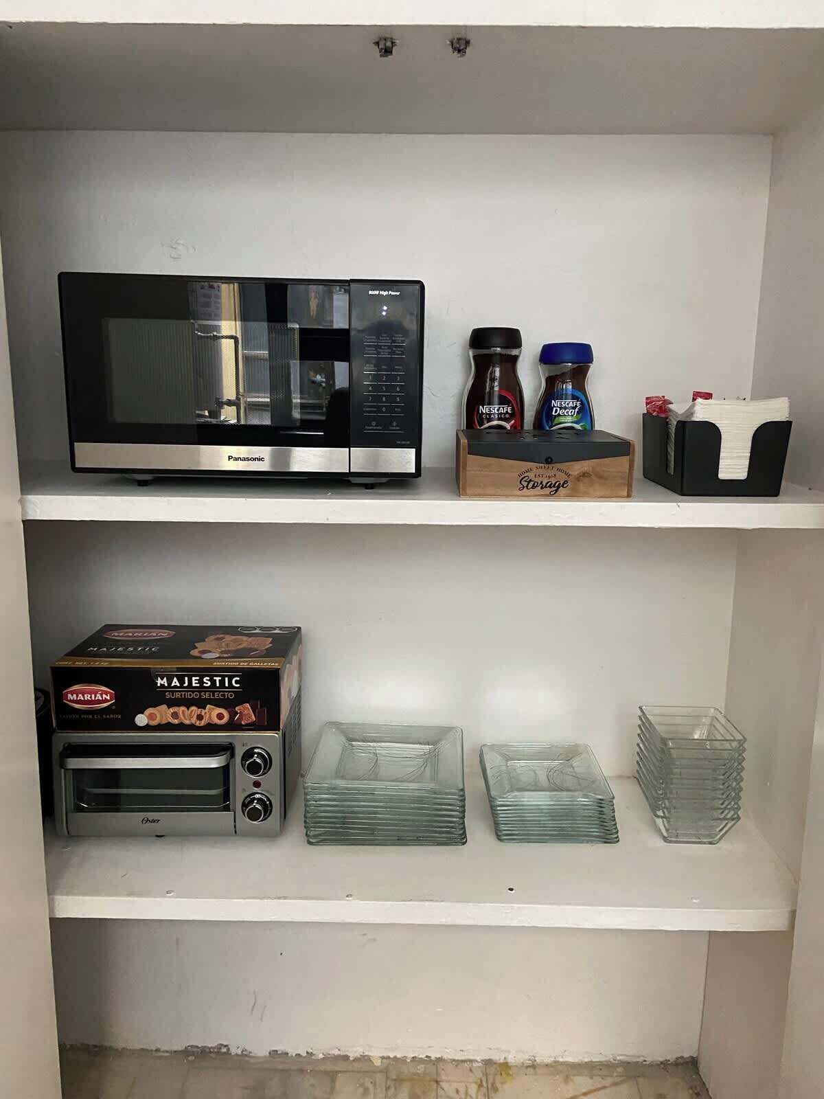 Une cuisine équipée d  ’un four à micro-ondes, d’un grille-pain et de récipients en verre rangés sur des étagères.