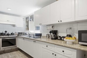 Eine moderne Küche mit weißen Schränken, einem eingebauten Backofen, einer Kaffeemaschine und einer Zitronenschale auf der Arbeitsplatte.