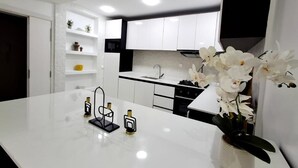 Eine moderne Küche mit weißen Schränken, einer Marmorarbeitsplatte und einer Vase mit weißen Orchideen.