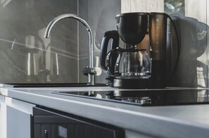 A modern kitchen with a coffee maker, a faucet, and a kettle.