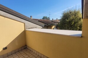 A yellow exterior wall with a white ledge, a tiled floor, and a clear blue sky. - CN041 - Cesenatico, four-room apartment on two levels with accessories (Cesenatico)