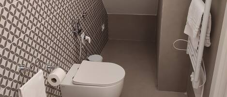 A bathroom with a patterned wall, a toilet, a bidet, and a towel rack.