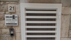 Ein weißes Fenster mit horizontalen Jalousien, eine Tür und ein Schild darüber.