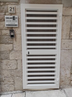 Ein weißes Fenster mit horizontalen Jalousien, eine Tür und ein Schild darüber.