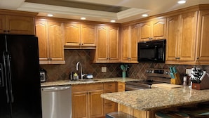 A kitchen with wooden cabinets, a stainless steel refrigerator, a microwave, a dishwasher, and a granite countertop. - 2-bedroom townhome in peaceful Fort Myers with AC (Fort Myers)
