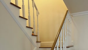 A staircase with wooden steps and white balusters, leading to a landing. - 2-bedroom townhome in peaceful Fort Myers with AC (Fort Myers)