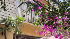 A patio with a black wicker sofa, a large potted plant, and a hanging planter with pink flowers. - 2-bedroom townhome in peaceful Fort Myers with AC (Fort Myers)