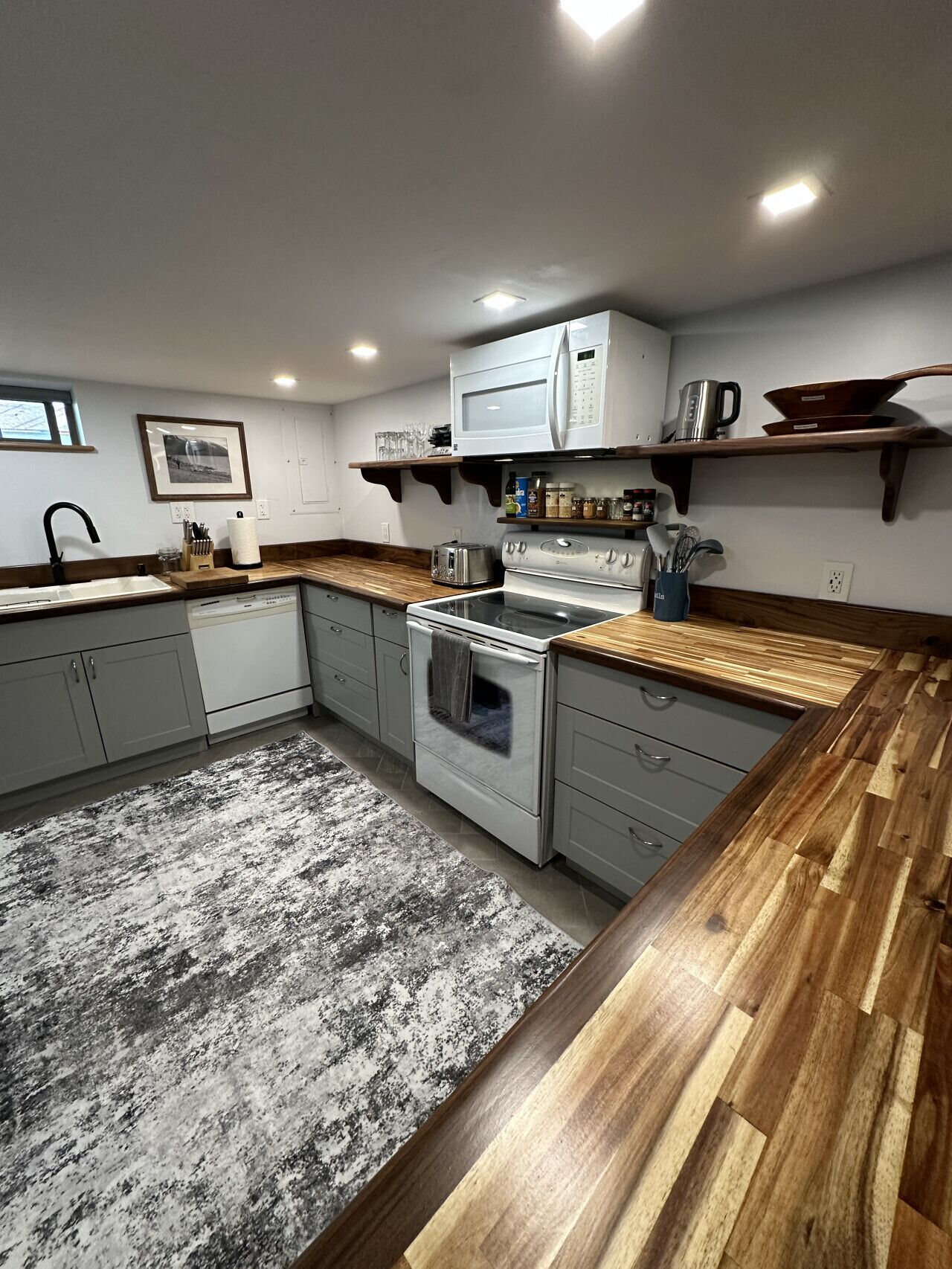 Une cuisine équipée d’une cuisinière, d’un four à micro-ondes et de plans de travail en bois.