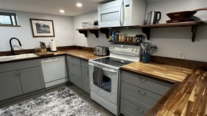 A kitchen with a stove, microwave, and wooden countertops. - Short walk to downtown & Flathead Lake (Polson)