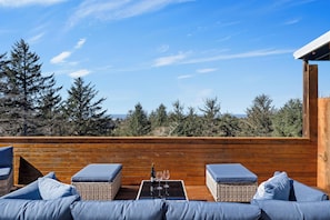Eine Holzterrasse mit Korbmöbeln und einem Tisch, auf dem eine Flasche und Gläser stehen.