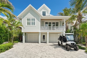 Ein zweistöckiges Haus mit Garage, Balkon und einem Golfwagen vor der Tür.
