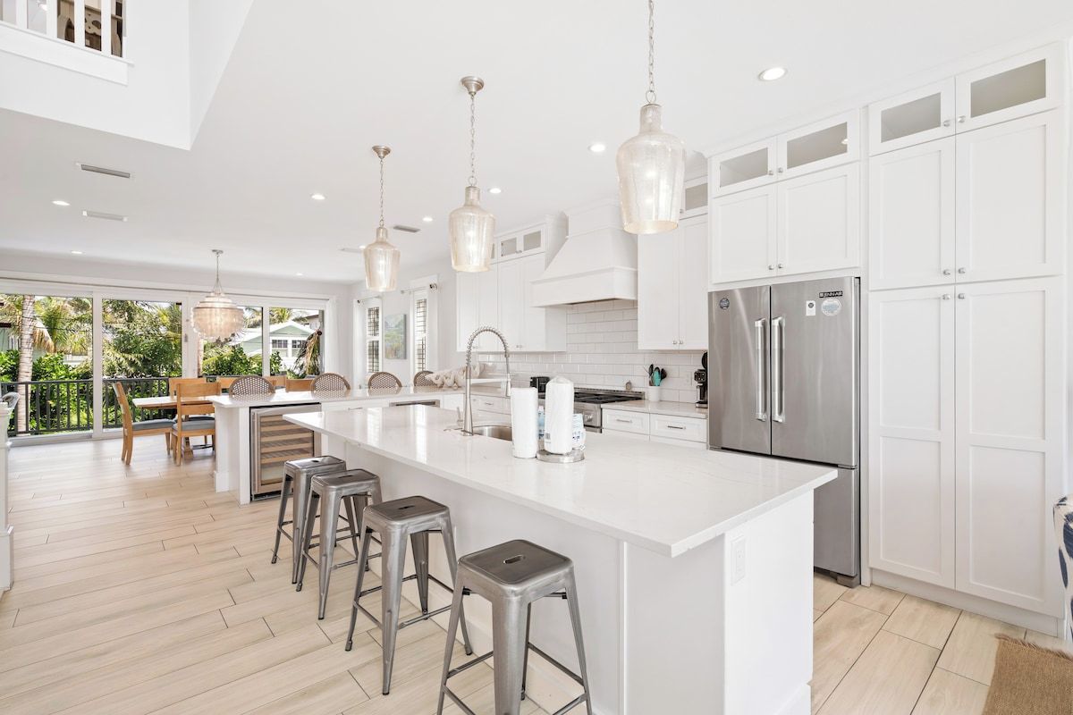 A modern kitchen with a large island, stainless steel appliances, and pendant lighting.