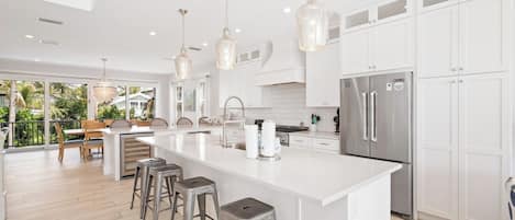 A modern kitchen with a large island, stainless steel appliances, and pendant lighting.