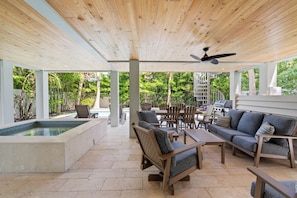 Eine Terrass mit Pool, Holzmöbeln und Deckenventilator.