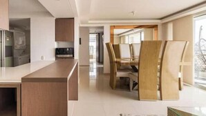 A modern kitchen with a central island, a dining area with a wooden table and chairs, and a view through a large window. - Luxo no Vale do Lili (Cali)